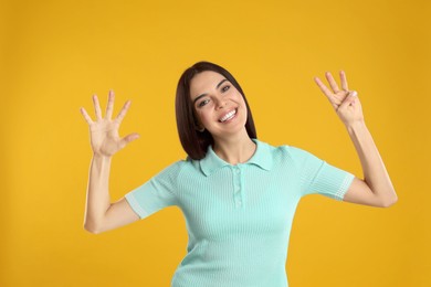 Woman showing number eight with her hands on yellow background
