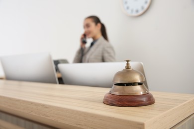 Photo of Receptionist working at counter in hotel, focus on bell