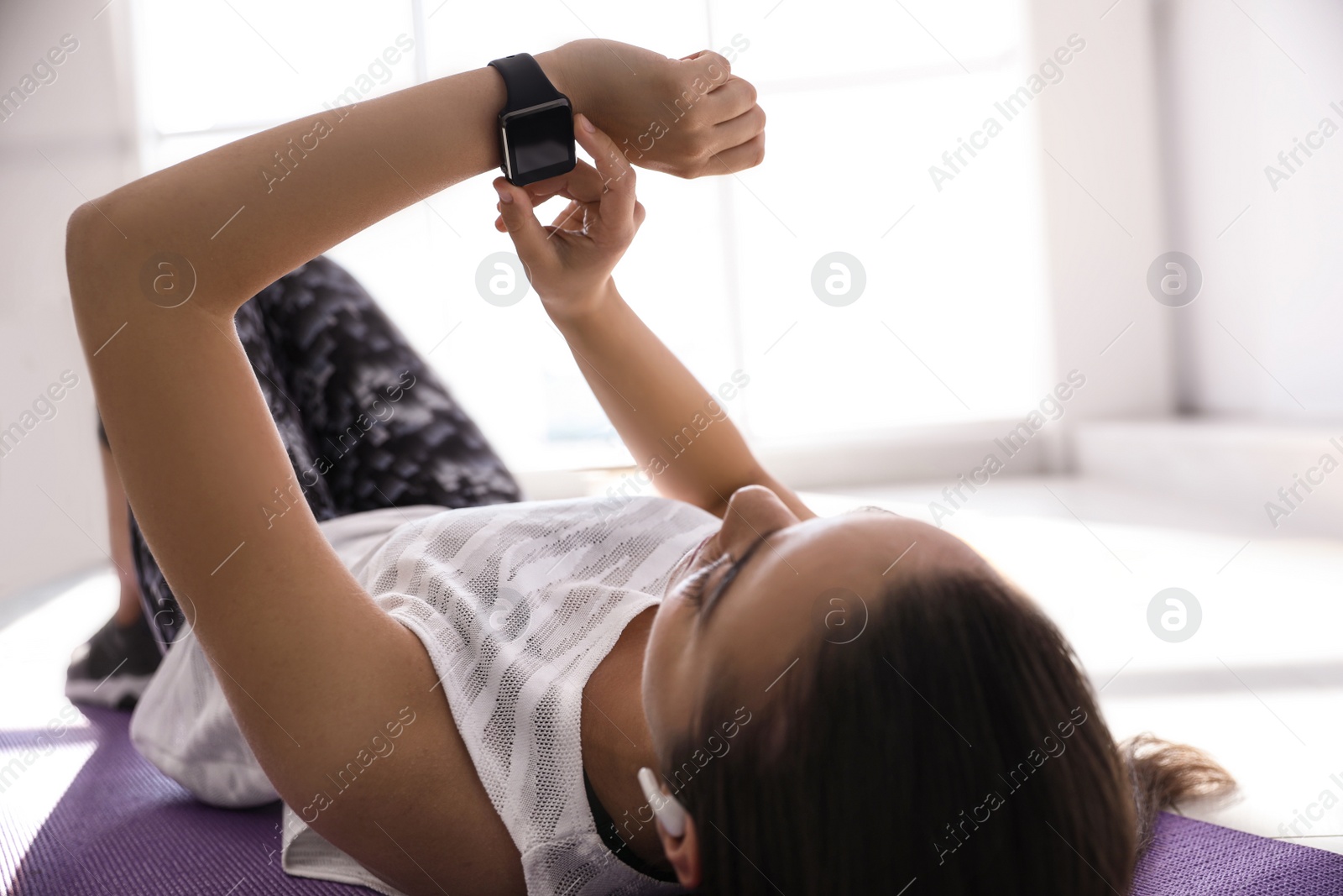 Photo of Woman checking fitness tracker during training in gym