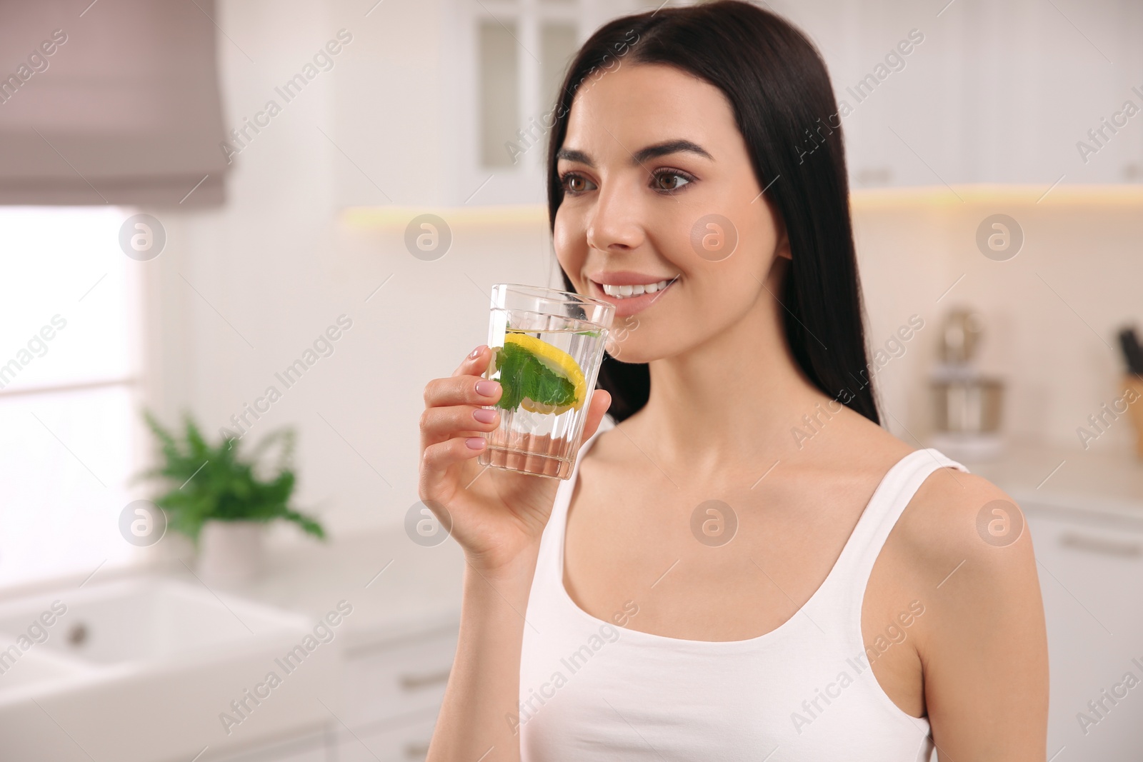 Photo of Young woman with glass of fresh lemonade at home