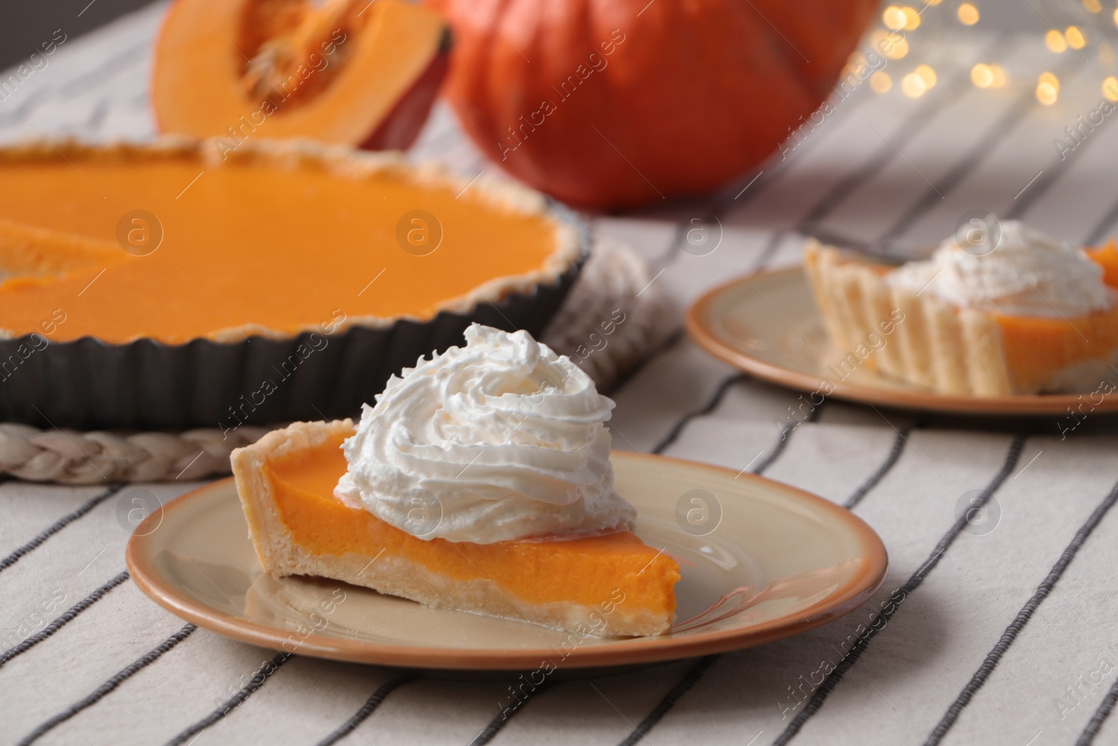 Photo of Piece of fresh homemade pumpkin pie with whipped cream on table