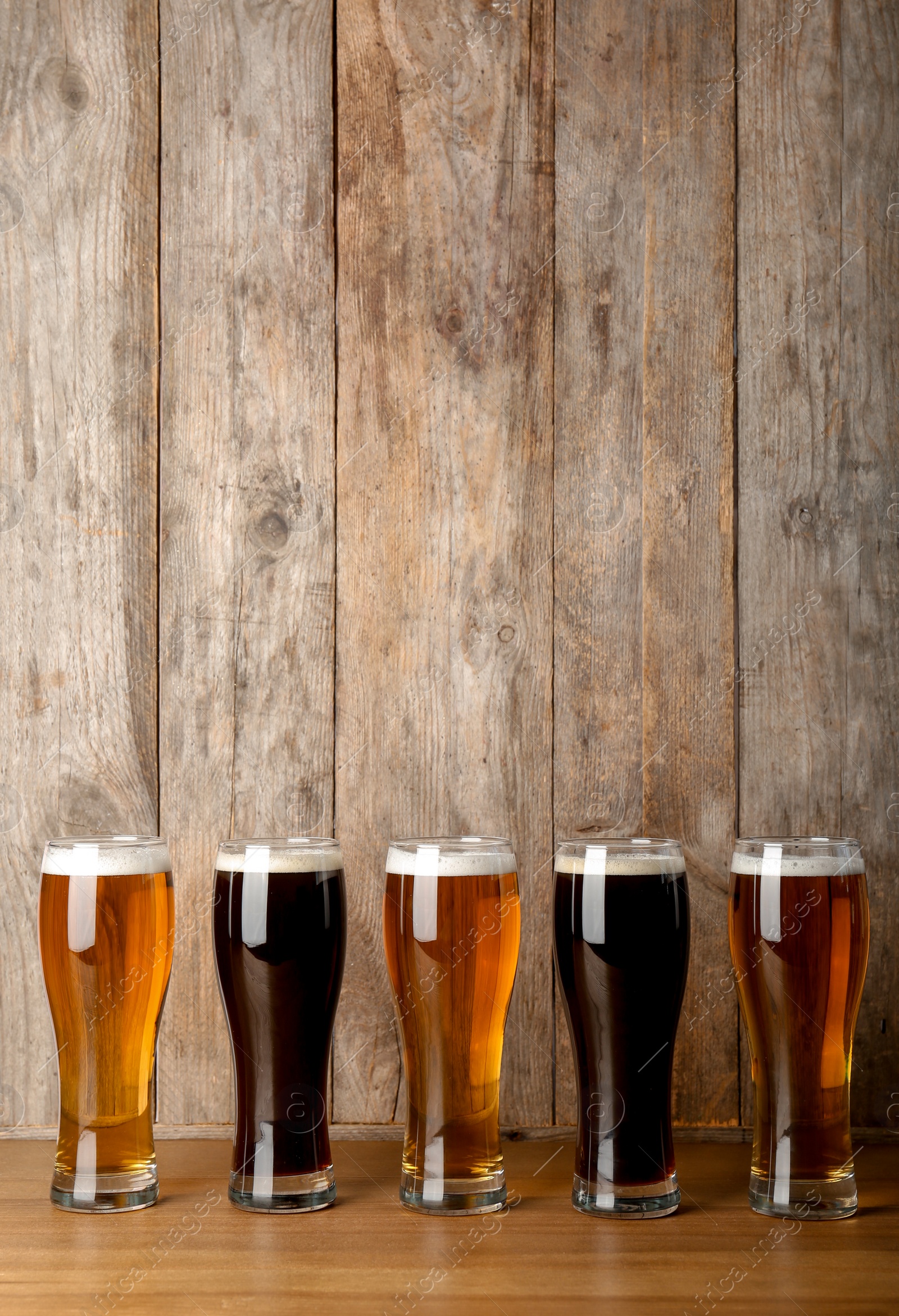 Photo of Glasses with beer on table against wooden background