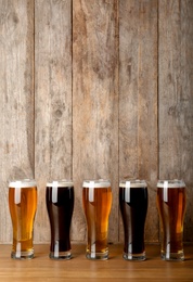 Photo of Glasses with beer on table against wooden background