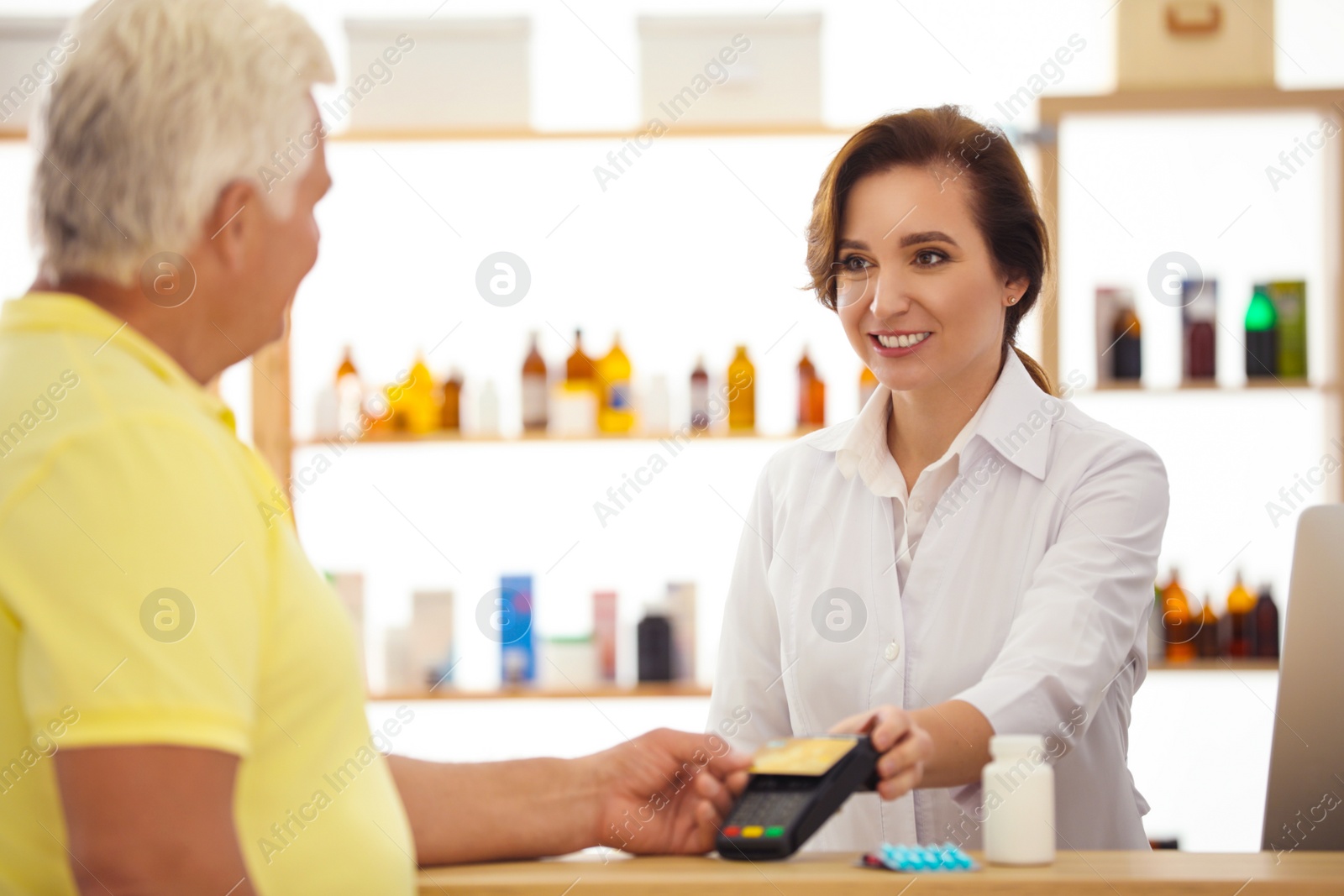 Photo of Customer using terminal for contactless payment with credit card in pharmacy