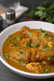 Photo of Delicious chicken with curry sauce on grey wooden table, closeup