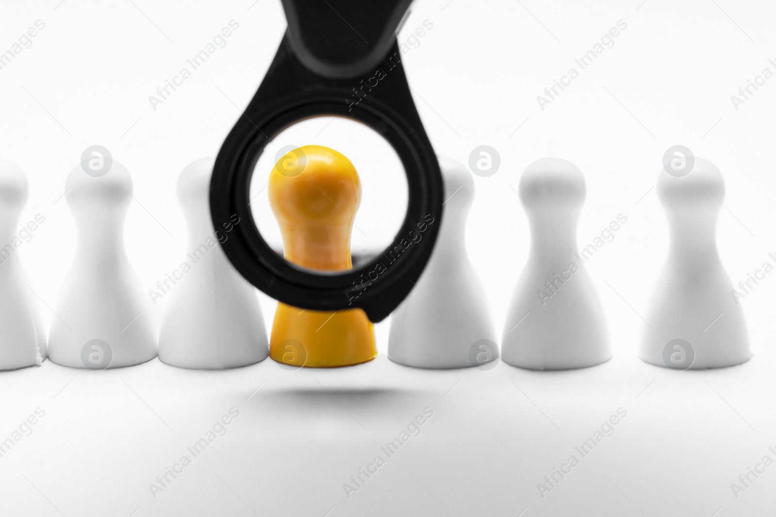 Photo of Magnifying glass near yellow pawn on white background. Recruiter searching employee