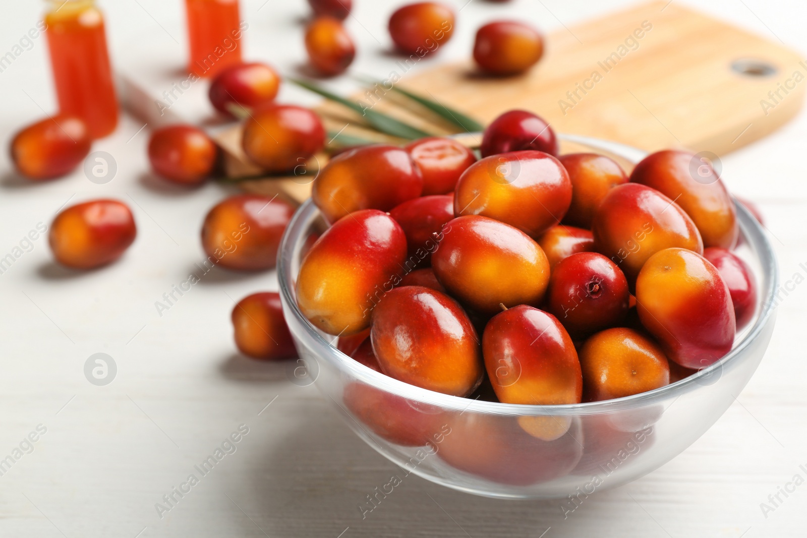 Image of Palm oil fruits in bowl on white wooden table, closeup