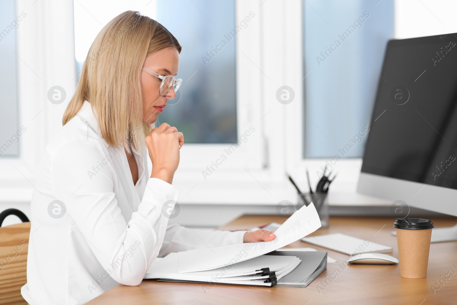 Photo of Woman working with documents at wooden table in office