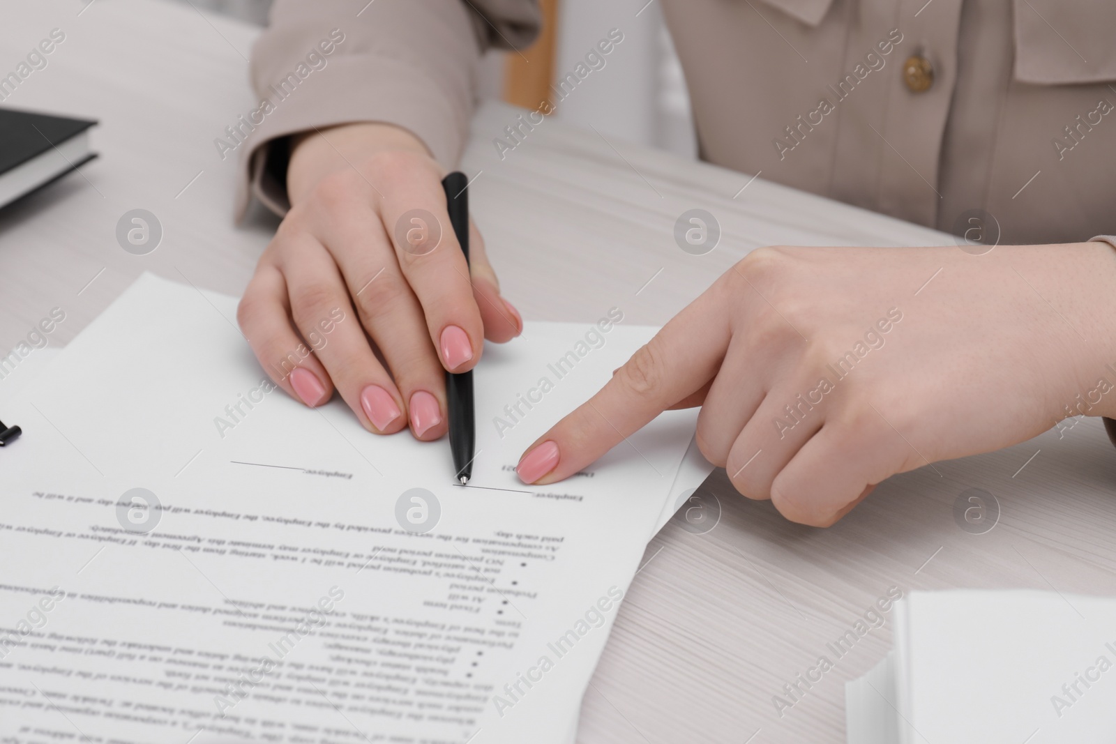 Photo of Woman signing document at wooden table, closeup