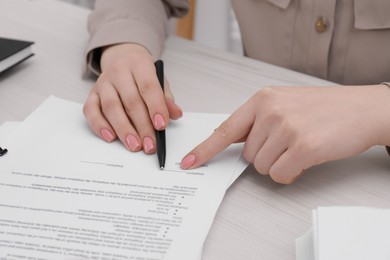 Woman signing document at wooden table, closeup