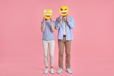 Photo of People covering faces with emoticons on pink background