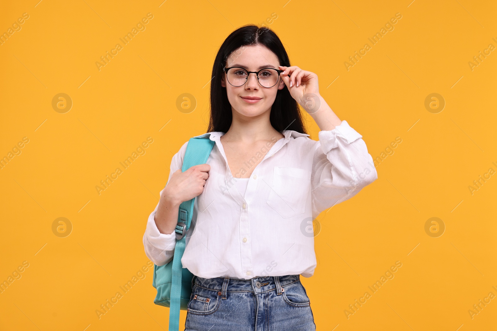 Photo of Student in glasses with backpack on yellow background