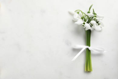 Photo of Beautiful bouquet of snowdrops on light table, top view. Space for text