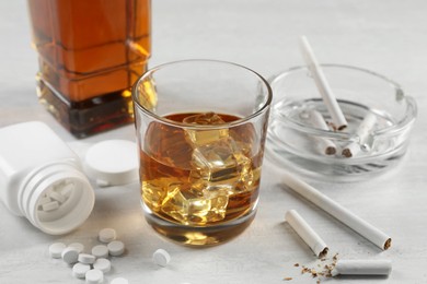 Photo of Alcohol and drug addiction. Whiskey in glass, cigarettes and pills on white table