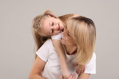 Family portrait of happy mother and daughter on grey background