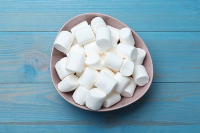 Photo of Delicious puffy marshmallows on light blue wooden table, top view