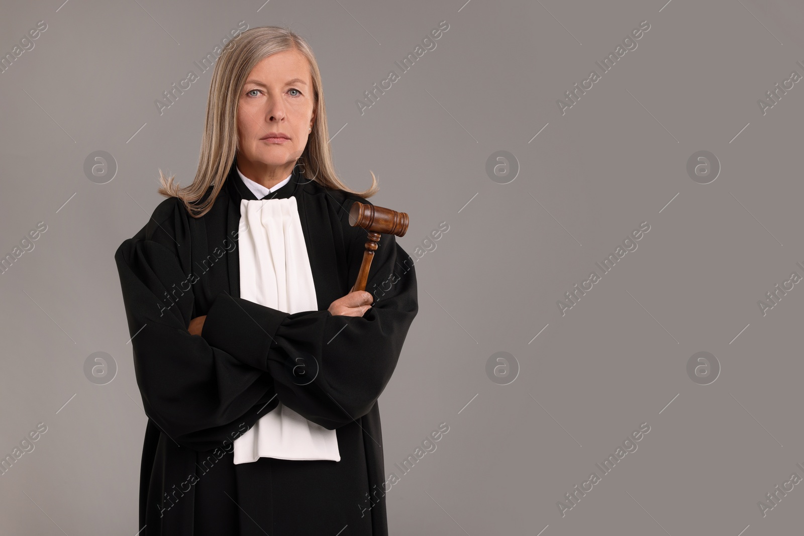 Photo of Senior judge with gavel on grey background. Space for text