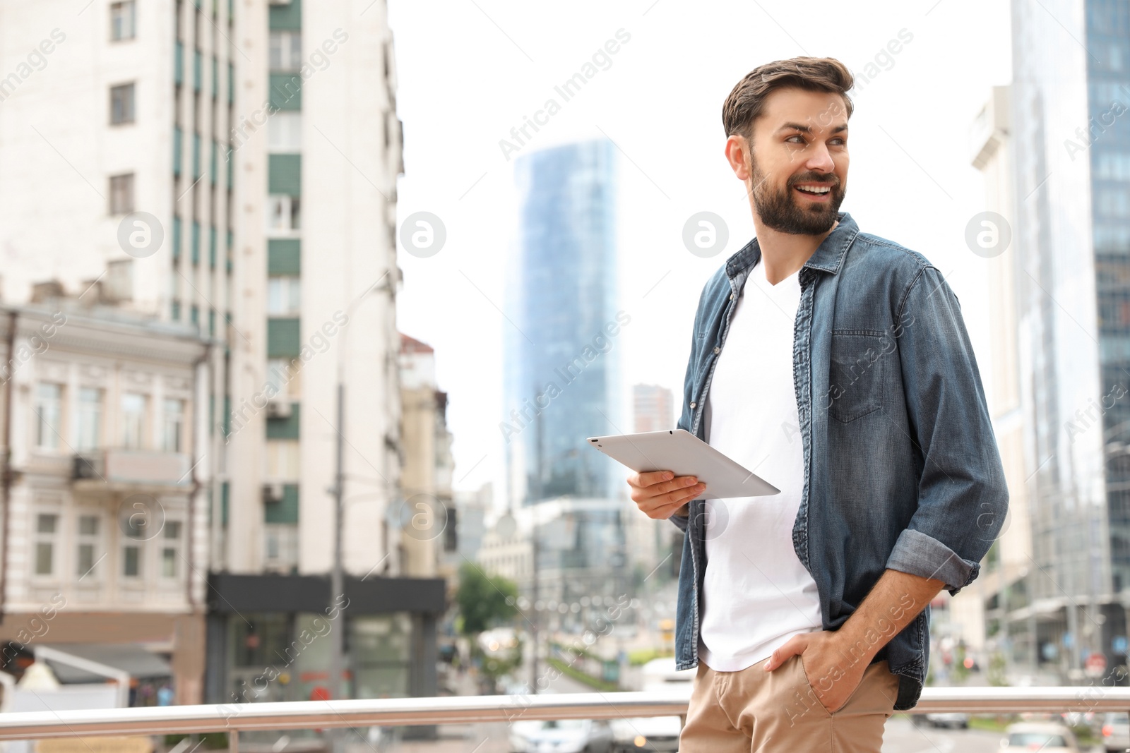 Photo of Handsome man working with tablet on city street