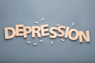 Photo of Word Depression made of wooden letters and pills on grey background, flat lay