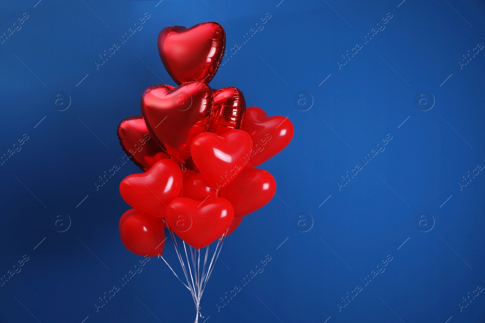 Photo of Bunch of heart shaped balloons on blue background, space for text. Valentine's day celebration