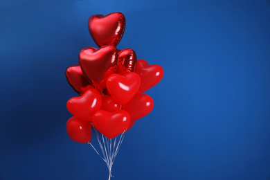 Photo of Bunch of heart shaped balloons on blue background, space for text. Valentine's day celebration