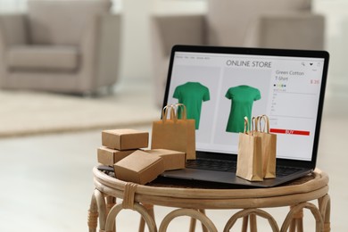 Online store. Laptop, small shopping bags and mini parcels on table indoors