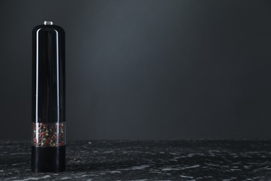 Pepper shaker on dark marble table, closeup. Space for text