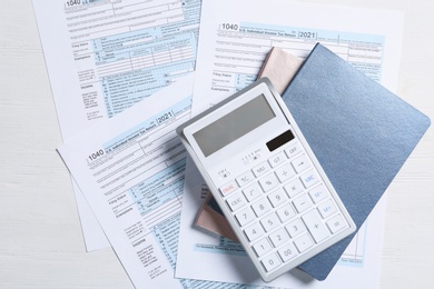 Photo of Calculator, notebooks and documents on white table, flat lay. Tax accounting