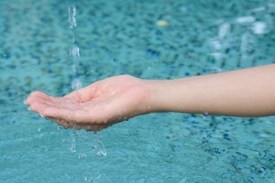 Water pouring into the girl's hand above pool, closeup