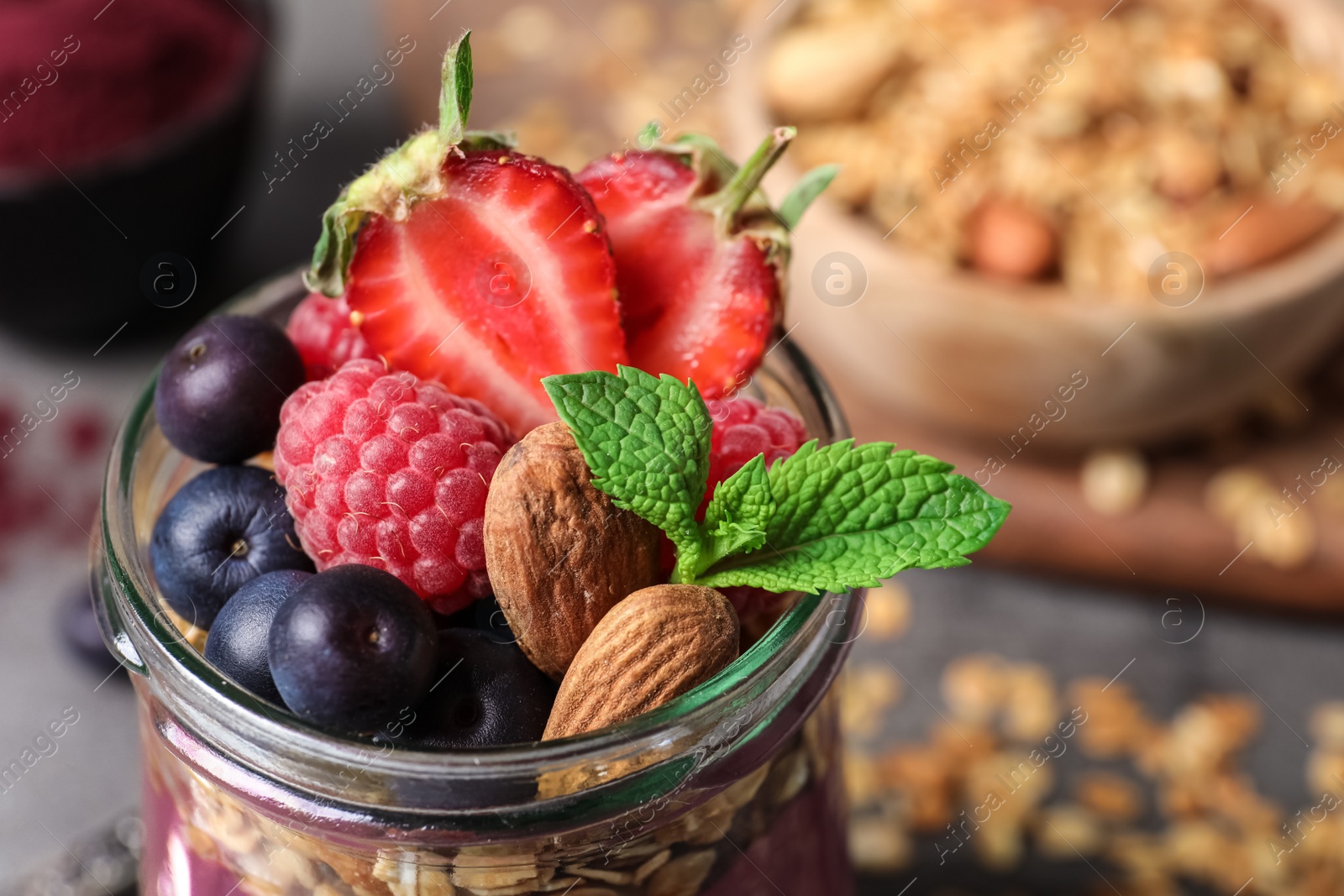 Photo of Delicious acai dessert with granola and berries served on grey table, closeup