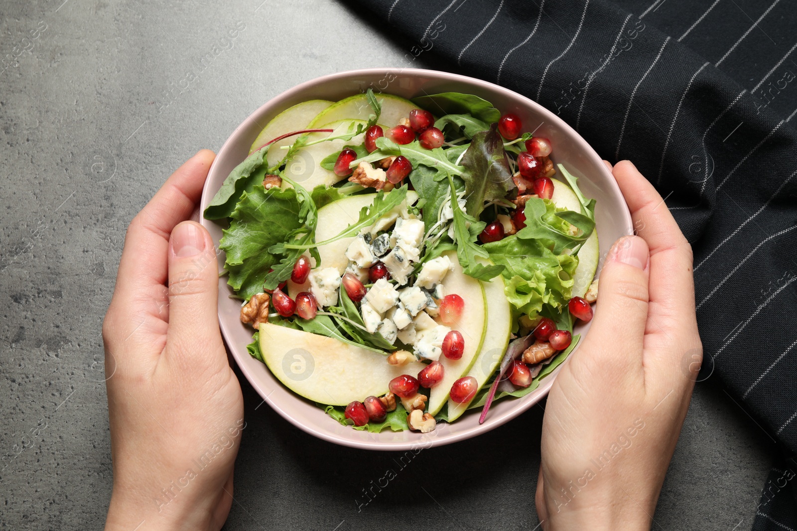 Photo of Woman with tasty pear salad at grey table, top view