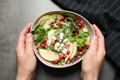 Woman with tasty pear salad at grey table, top view