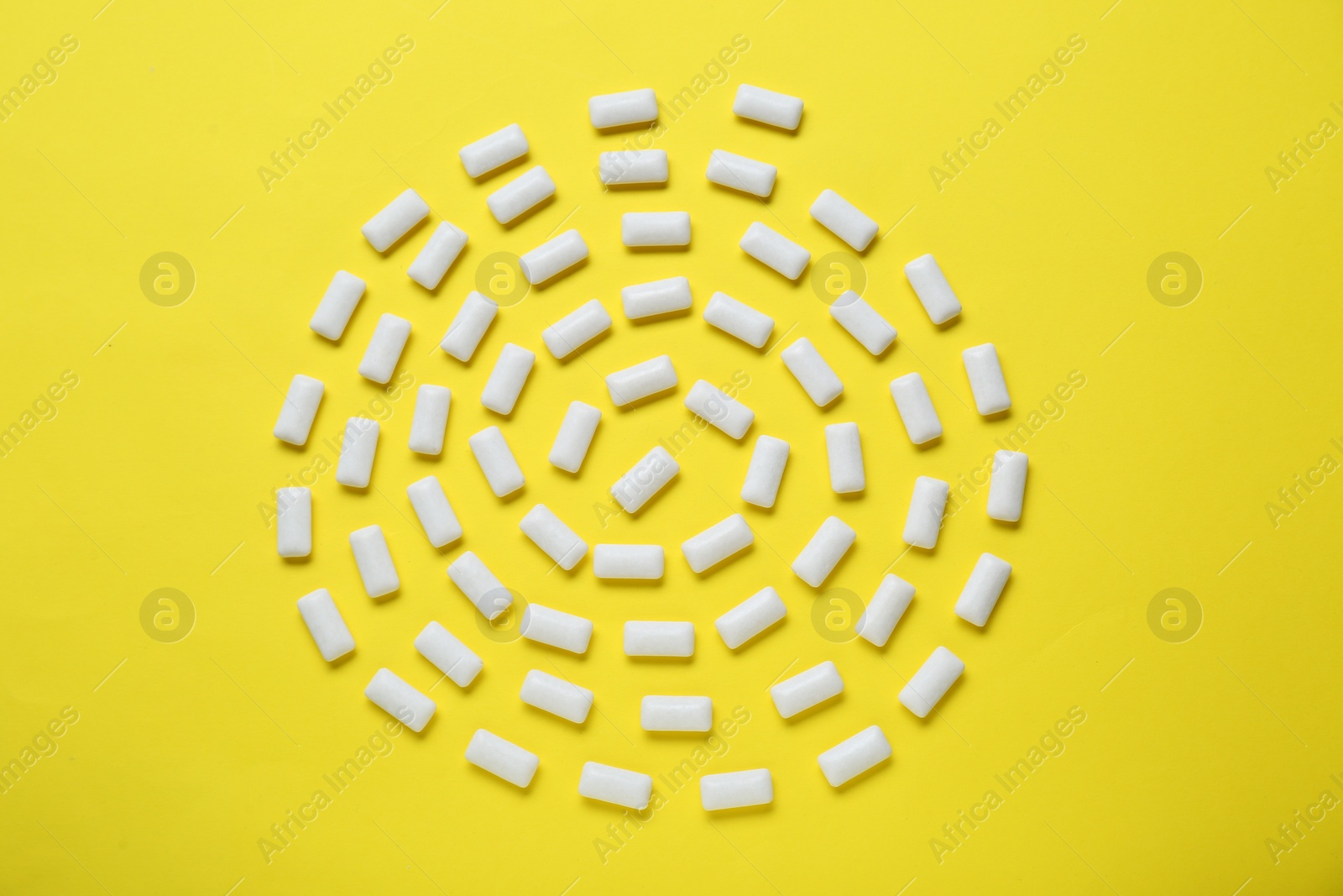 Photo of Tasty white chewing gums on yellow background, flat lay