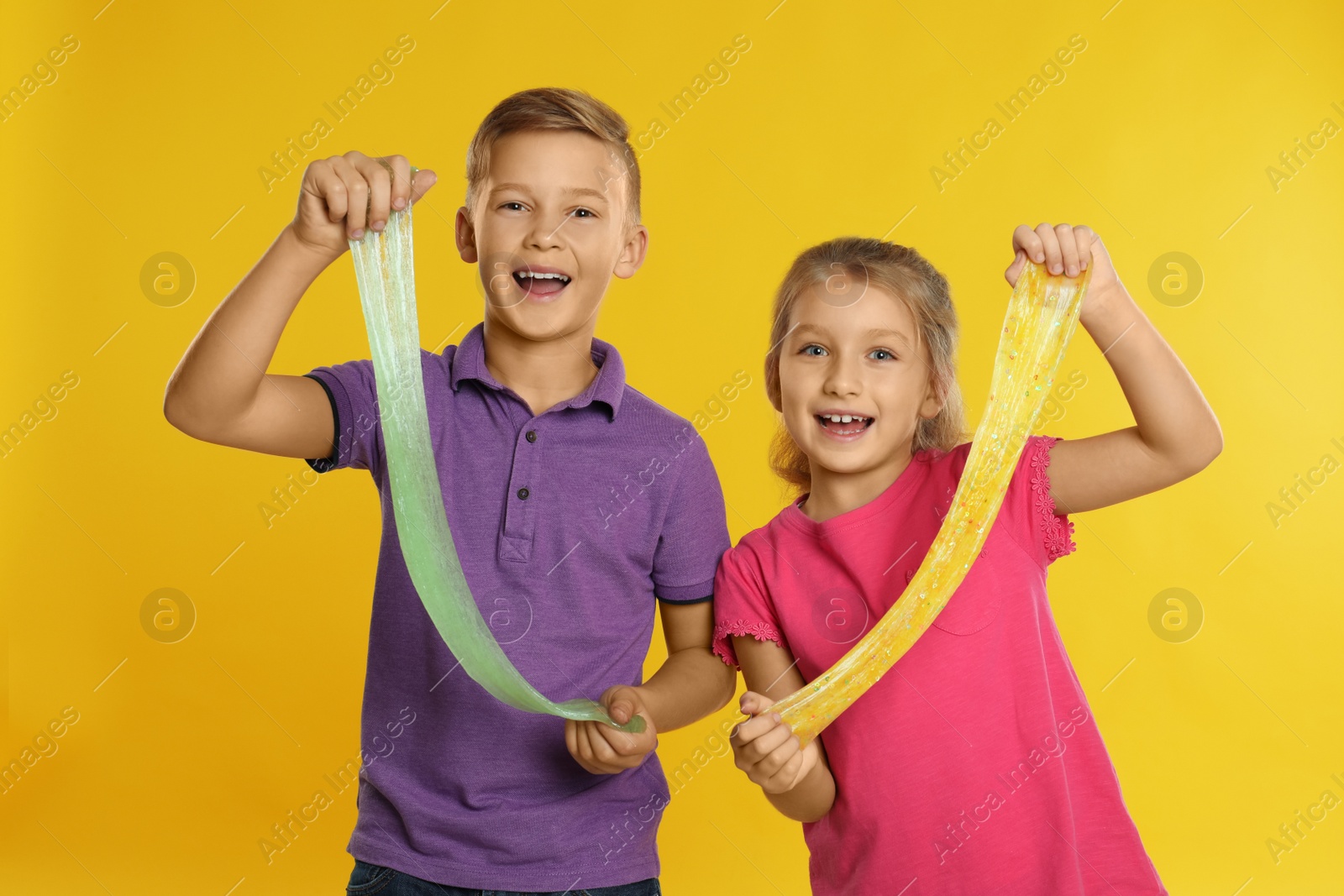 Photo of Happy children with slime on yellow background