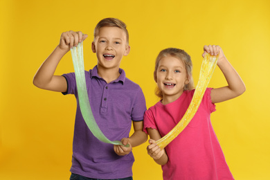 Happy children with slime on yellow background