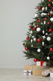 Photo of Beautifully decorated Christmas tree and many gift boxes in room, space for text