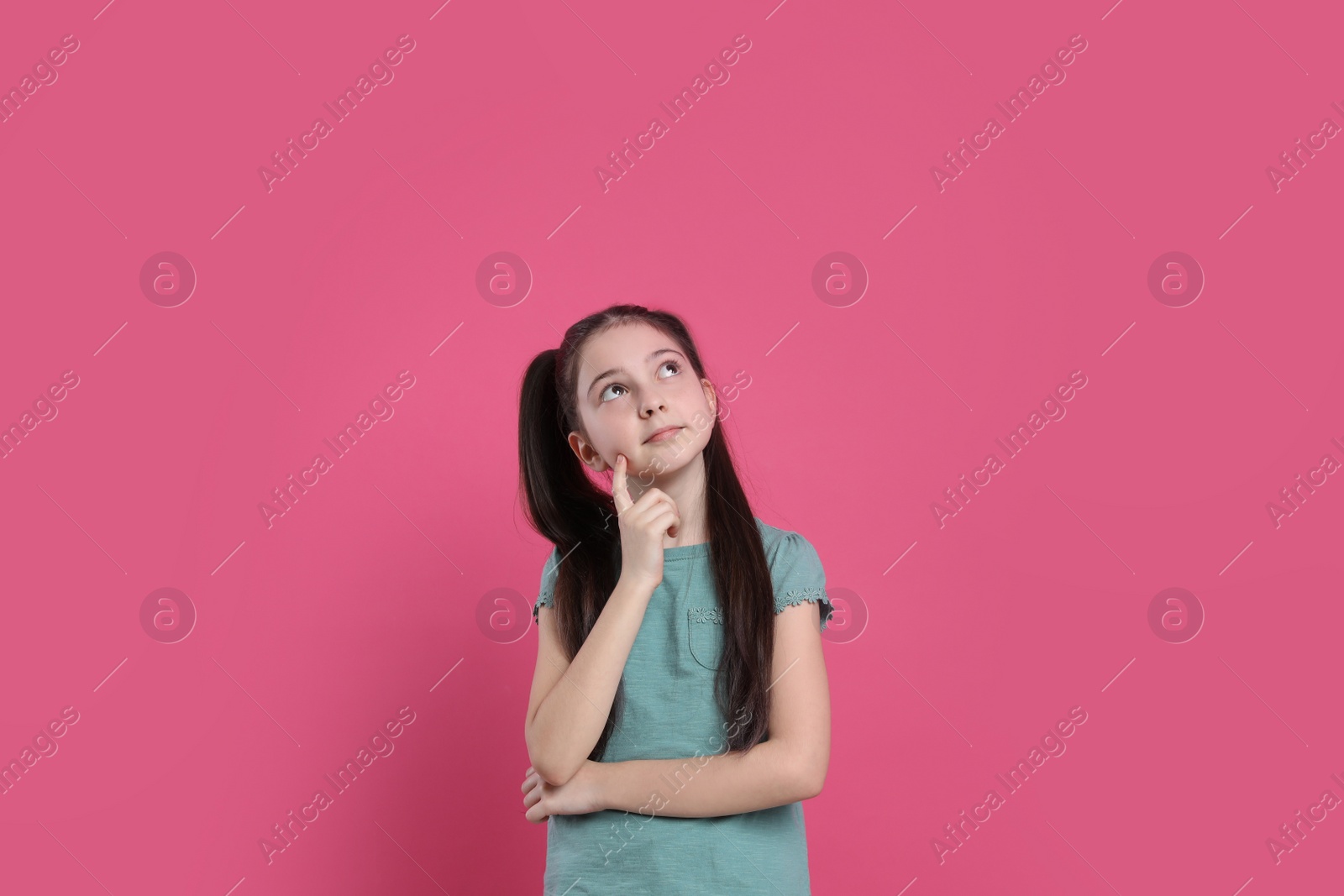 Photo of Portrait of pensive little girl on pink background. Thinking about answer for question