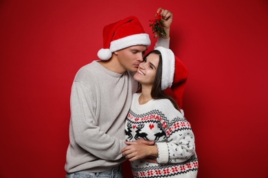 Photo of Happy couple under mistletoe bunch on red background