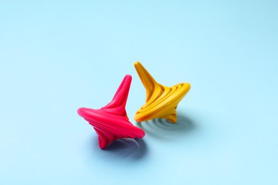 Photo of Yellow and pink spinning tops on light blue background, closeup