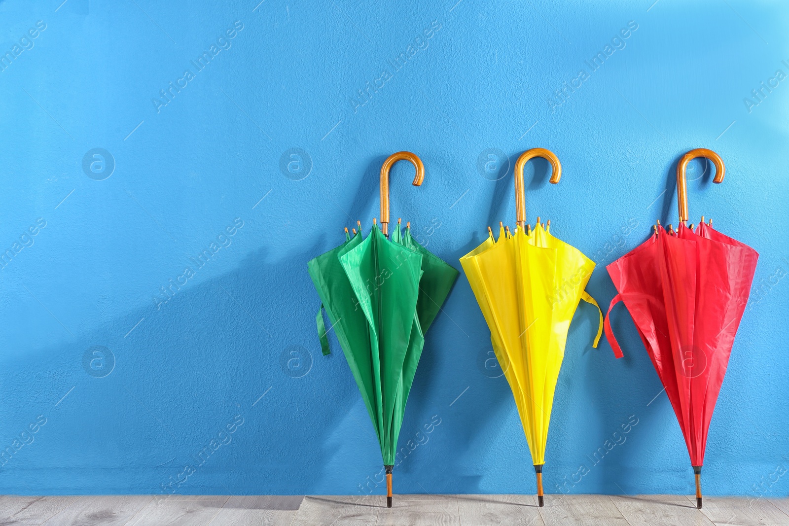 Photo of Beautiful closed colorful umbrellas near blue wall
