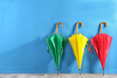 Beautiful closed colorful umbrellas near blue wall