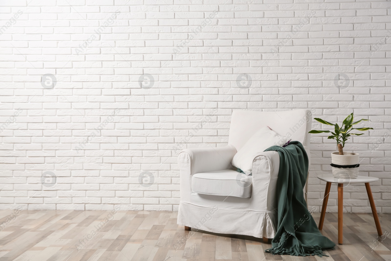 Photo of Comfortable armchair near brick wall in modern room interior. Space for text