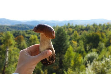 Photo of Man holding fresh wild mushroom on sunny autumn day, closeup. Space for text