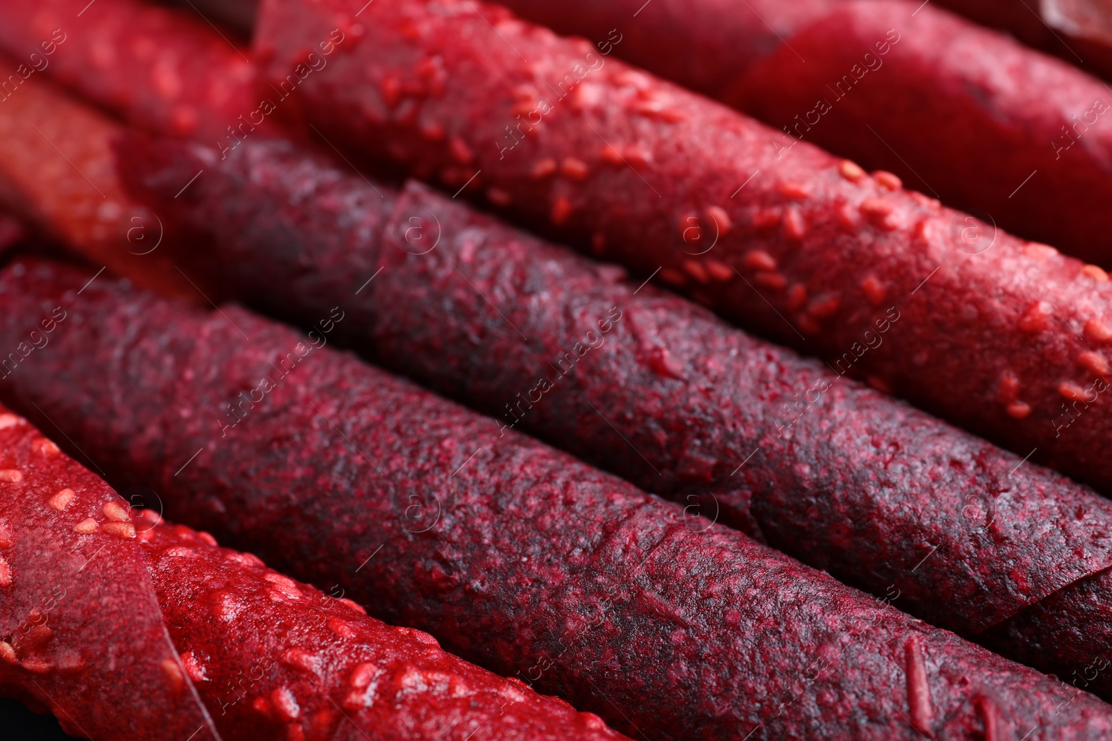 Photo of Delicious fruit leather rolls as background, closeup