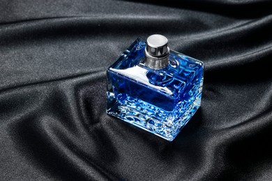 Luxury men's perfume in bottle on black satin fabric