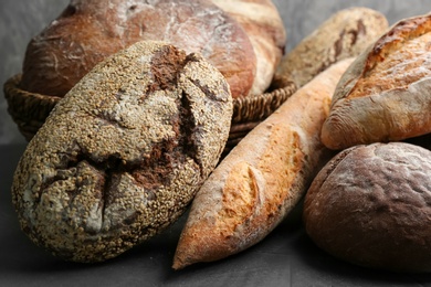 Photo of Different kinds of fresh bread on grey table, closeup