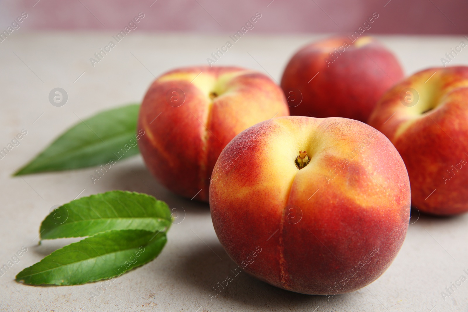 Photo of Fresh juicy peaches and leaves on light table