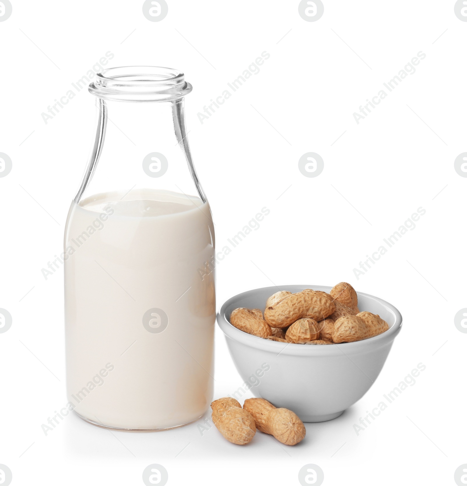 Photo of Bottle with peanut milk and nuts on white background