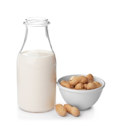 Photo of Bottle with peanut milk and nuts on white background