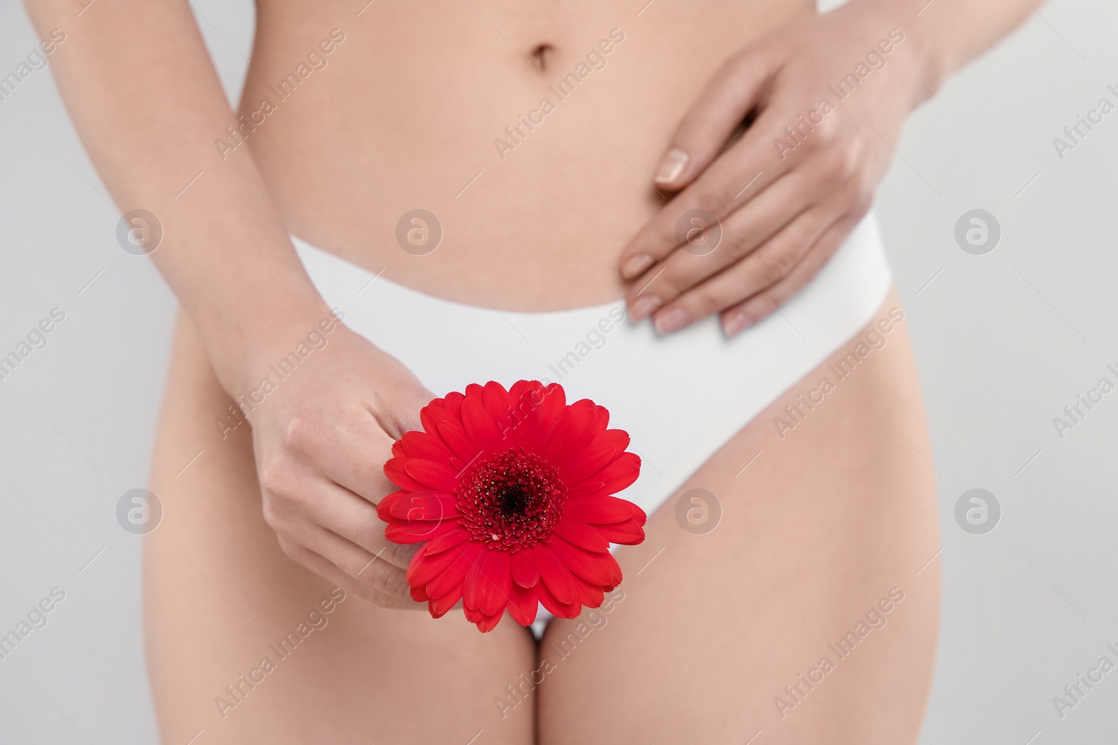 Photo of Gynecology. Woman in underwear with gerbera flower on light background, closeup